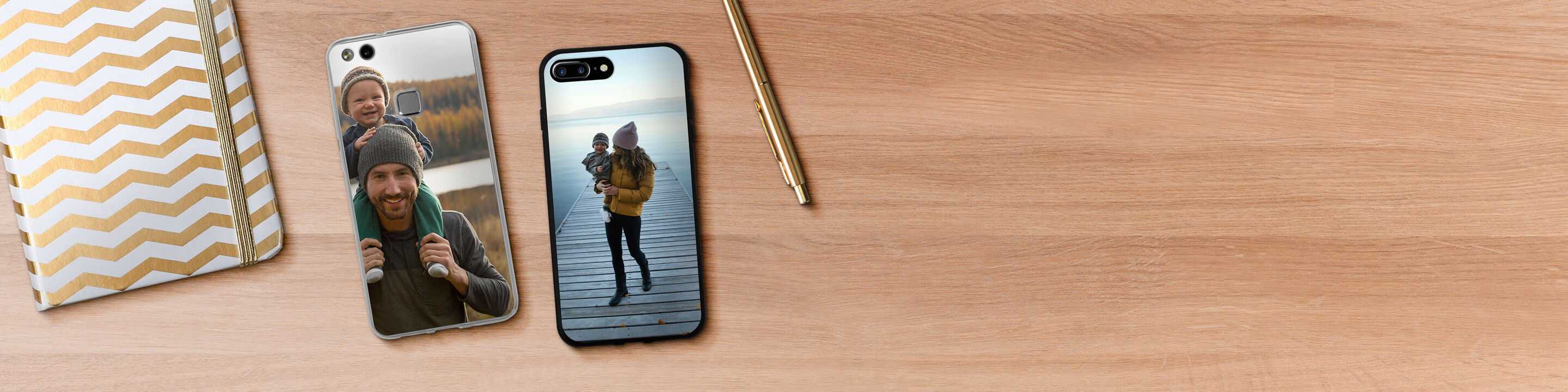Due custodie per cellulari personalizzate con foto, su un tavolo di legno con una penna d'oro e un taccuino.