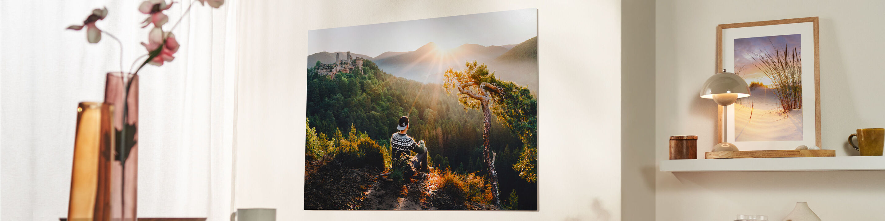 Un quadro con una persona che cammina in un paesaggio incantevole, circondata da raggi di sole e alberi, nel soggiorno di una casa moderna.