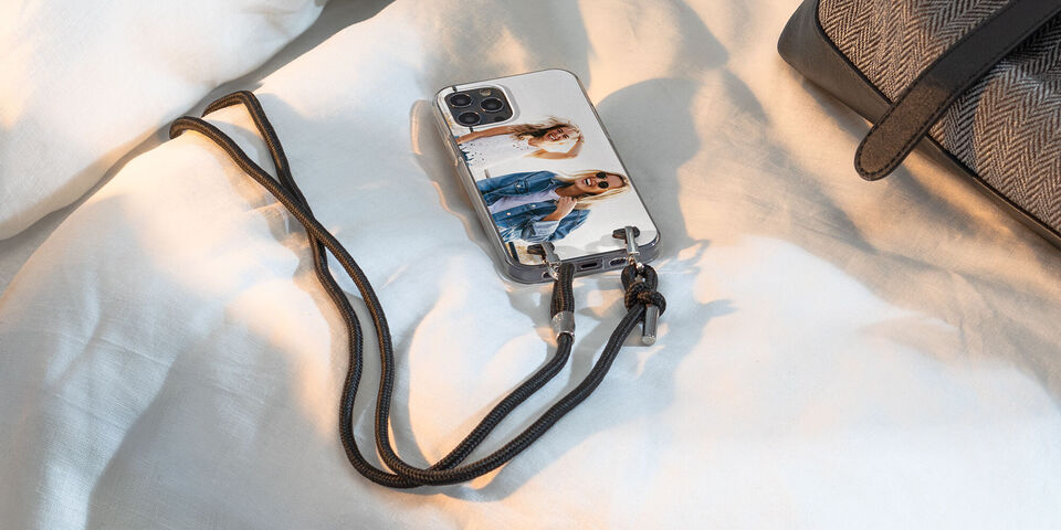 Una custodia per smartphone con due amiche sorridenti su un letto bianco.
